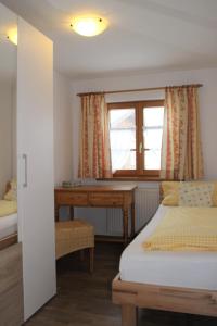 een slaapkamer met een bureau, een bed en een raam bij Haus & Heim Ferienwohnung in Oberstdorf
