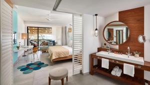 a bathroom with a bed and a sink and a mirror at C Mauritius in Belle Mare