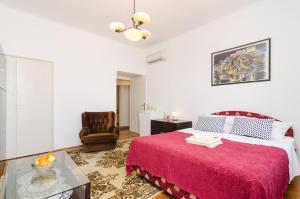 a bedroom with a red bed and a chair at Apartments Davor in Dubrovnik