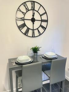 a dining room table with a large clock on the wall at Cannock, Modern 2 bed house, Perfect for contractors, Business Travellers, Short Stays, Driveway for 2 vehicles, Close to M6, M54/i54, A5.A38. McArthur Glen Designer Outlet in Cannock