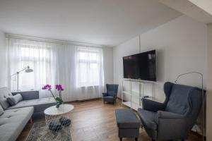 - un salon avec un canapé, des chaises et une télévision dans l'établissement Ferienwohnung Alte Meierei, à Gelting
