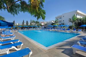 a large swimming pool with blue chairs and umbrellas at Euronapa Hotel Apartments in Ayia Napa