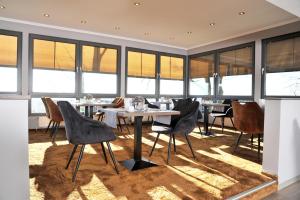 a dining room with a table and chairs and windows at Am Berghang in Bad Bentheim