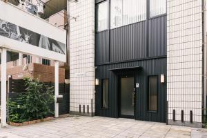 una puerta negra en un edificio con una acera en Guest House Yasuragi Hakataekimae en Fukuoka