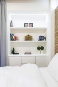 a white room with a bed and shelves with books at K2 SUITE in Thessaloniki