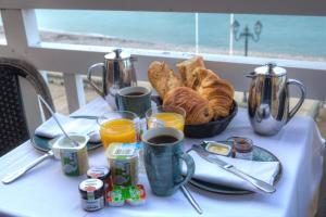 a table with a breakfast of bread and croissants at Hotel Le Rayon Vert in Étretat