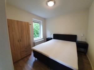a bedroom with a large bed and a window at Camping Alkenhaer Appelscha Bungalow in Appelscha
