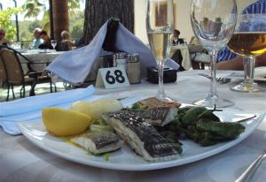 une assiette de poisson et de légumes sur une table avec des verres à vin dans l'établissement Luxurious flat with splendid views, à Orihuela Costa