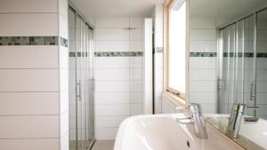 een witte badkamer met een wastafel en een douche bij Appartementen Natuurlijk in Egmond aan Zee +22 foto's