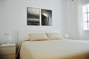 a white bedroom with a bed and two pictures on the wall at Fantastic 1 bedroom apartment in the centre of Nerja in Nerja