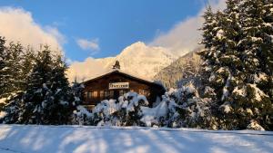 a log cabin in the snow with snow covered trees at L'Arveyron Open House in Chamonix