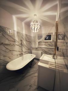 a bathroom with a bath tub and a chandelier at Berg Apartment in Braşov