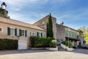 a large house with green shutters and a garage at Best Western Le Val Majour in Fontvieille