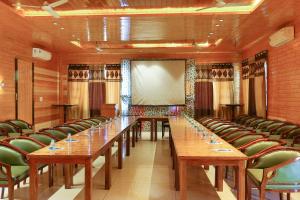 una sala de reuniones con mesas largas y sillas verdes en Comfort Inn Coral River, en Mādhopur