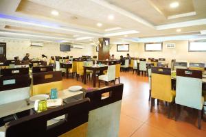 a restaurant with tables and chairs and people in the background at Comfort Inn Coral River in Mādhopur