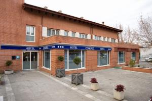 a red brick building with a blue sign on it at Hotel Cisneros in Alcalá de Henares