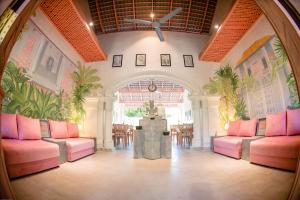 Villa Don Bastian في تانجالي: غرفة بها كراسي وردية وتمثال في الوسط