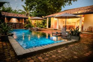 a swimming pool with an umbrella and a house at Villa Don Bastian in Tangalle