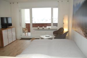 1 dormitorio con 1 cama, TV y ventana en Ferienwohnung mit Aussicht, en Enzklösterle