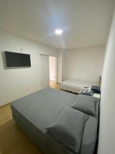 1 dormitorio con 2 camas y TV de pantalla plana en AP FRENTE À PRAÇA BEM LOCALIZADO 02 en São José