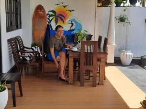 un hombre sentado en una mesa en una habitación en Ashen's Beach House, en Busse