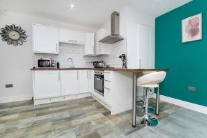 a kitchen with white cabinets and a green wall at Apartment 1 The Keyes- Stylish & Spacious Apartment With Free Parking in York