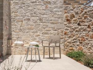 a chair and a table in front of a stone wall at Evaero Villas I, II, III, IV - an ever-so inviting escape, By ThinkVilla in Sfakaki