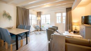 een woonkamer met een tafel, stoelen en een bank bij Appartementen Natuurlijk in Egmond aan Zee