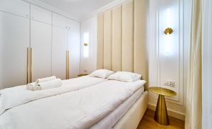 een slaapkamer met een groot wit bed en een tafel bij LAGUNA Apartament Polanica Residence 20 in Polanica-Zdrój