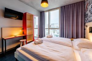 a bedroom with a large white bed and a window at MEININGER Hotel Bordeaux Gare Saint-Jean in Bordeaux