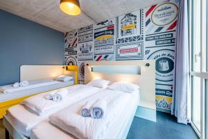 two beds in a room with a wall covered in stickers at MEININGER Hotel Bordeaux Gare Saint-Jean in Bordeaux