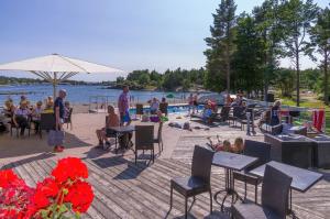 grupa ludzi siedzących przy stolikach na plaży w obiekcie Strandby Villas Käringsund w mieście Eckerö