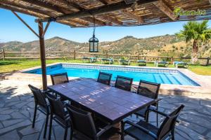 een patio met een tafel en stoelen naast een zwembad bij El Quinto Pino in Canillas de Albaida