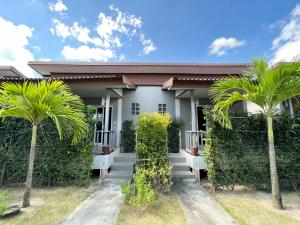 een huis met palmbomen ervoor bij CheeVa Beach Resort in Baan Tai