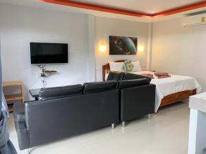 een slaapkamer met een bed, een bank en een tv bij CheeVa Beach Resort in Baan Tai