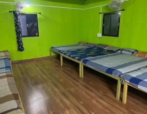 Habitación con 2 camas, paredes verdes y suelo de madera. en Dandeli Eco VanaVasa by StayApart, en Dandeli