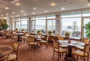 a restaurant with tables and chairs and large windows at Cosmos Petrozavodsk Hotel in Petrozavodsk