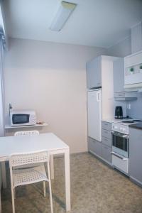 a kitchen with a white table and a white refrigerator at Stay Kymi kalustetut huoneistot in Kouvola