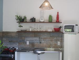 a kitchen with a brick wall and a white refrigerator at Pipa Family House in Pipa