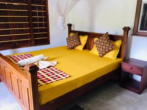 a large wooden bed with yellow sheets and pillows at MUM&DAD HOUSE in Dickwella