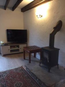 a living room with a stove and a tv at Dalesway cottage in Sedbergh