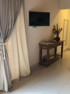 a room with a television and a table with curtains at Loft Caeté in Araruama