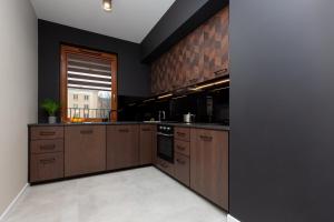 duża kuchnia z brązowymi szafkami i oknem w obiekcie Awangarda Apartment Warsaw Ochota by Renters Prestige w Warszawie