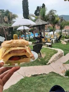 a person holding a plate with a sandwich on it at Complejo Los Cipreses in Villa Carlos Paz