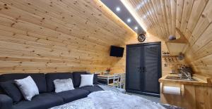 Loch Ewe Luxury Pods في Mellon Charles: غرفة معيشة مع أريكة زرقاء في جدار خشبي