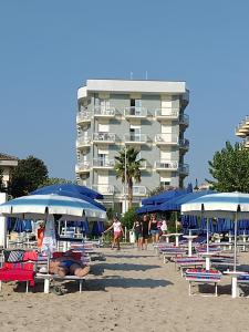 - un groupe de chaises longues et de parasols sur la plage dans l'établissement Hotel Boston, à Alba Adriatica