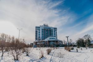 a tall building in the snow in front of a building at Cosmos Petrozavodsk Hotel in Petrozavodsk