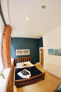 1 dormitorio con 1 cama con pared azul en Lovely Studio Apartment in the Heart of Nottingham en Nottingham