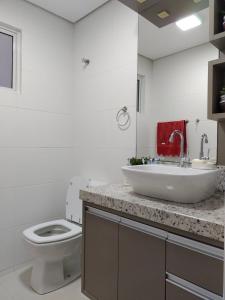 uma casa de banho branca com um lavatório e um WC em Apartamento Vida Boa em Gravatal