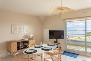 a dining room with a table and chairs and a television at HEOL - appartement 2 chambres - vue mer et parking in Dinard